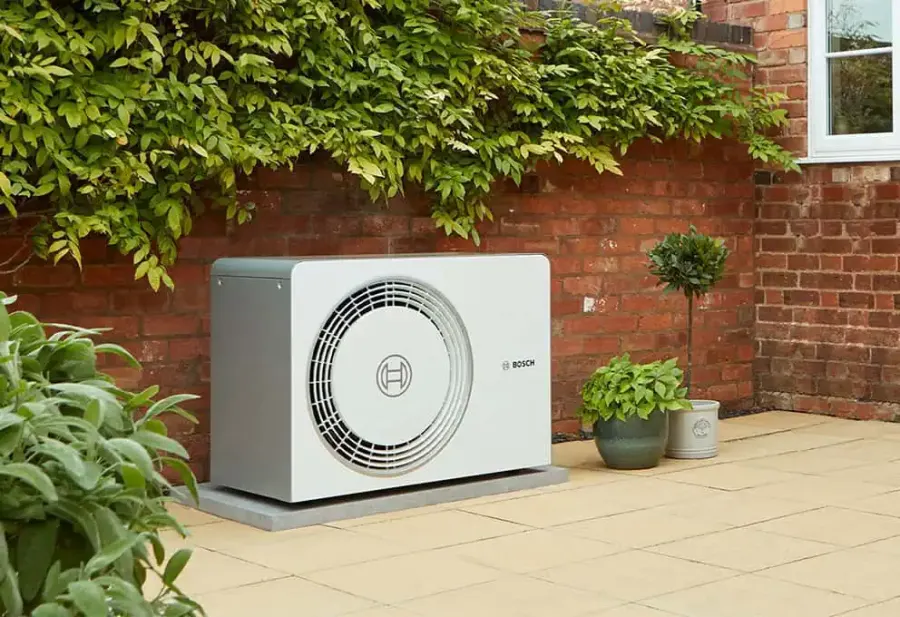 A Bosch air source heat pump on a patio against a brick garden wall